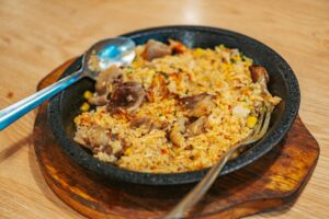 Delicious fried rice with meat, vegetables on a wooden board, perfect for a hearty meal.