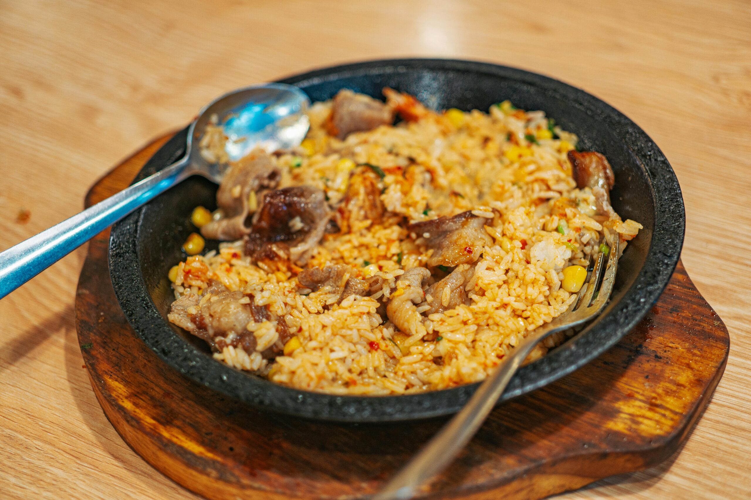 Delicious fried rice with meat, vegetables on a wooden board, perfect for a hearty meal.