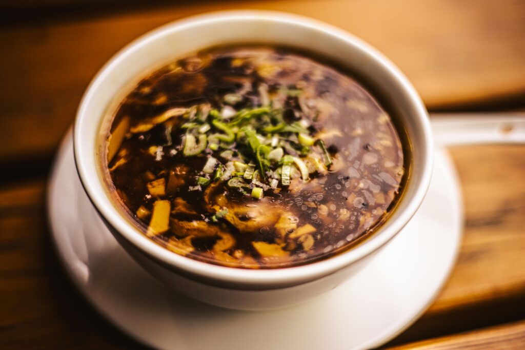 Appetizing hot and sour soup in a bowl garnished with fresh herbs.