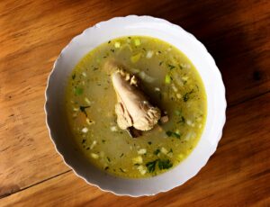 Delicious Ecuadorian chicken soup with vegetables in a white bowl, perfect for a comforting meal.