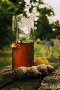 Chilled lemon ginger tea with fresh ingredients on rustic table, perfect for a summer refreshment.