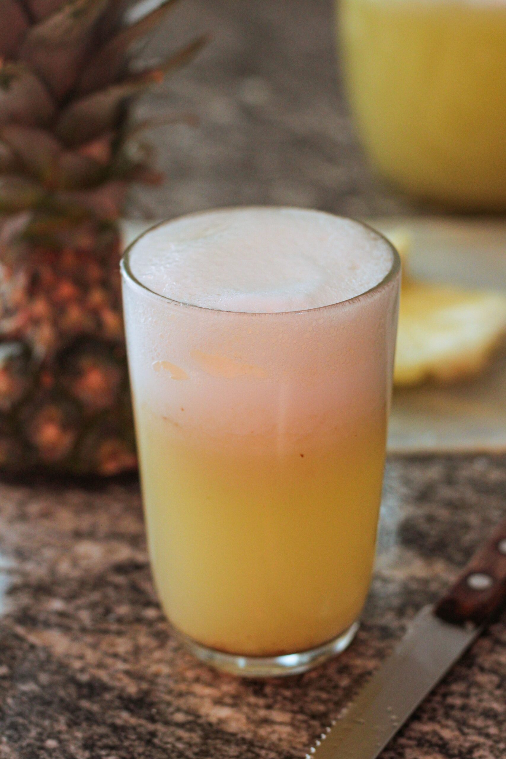Frothy pineapple smoothie drink in a glass, perfect for summer.
