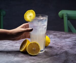 Refreshing iced lemonade garnished with lemon slices, served on a dark tabletop.
