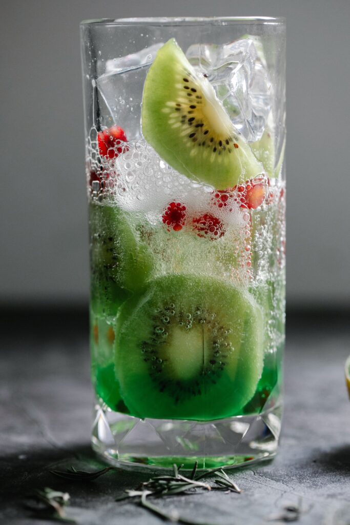 Close-up of a refreshing kiwi and pomegranate infused sparkling drink in a glass.